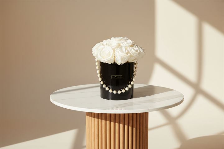Eternal rose named Audrey by Esor Atelier, beautifully preserved with soft pink petals and green leaves.